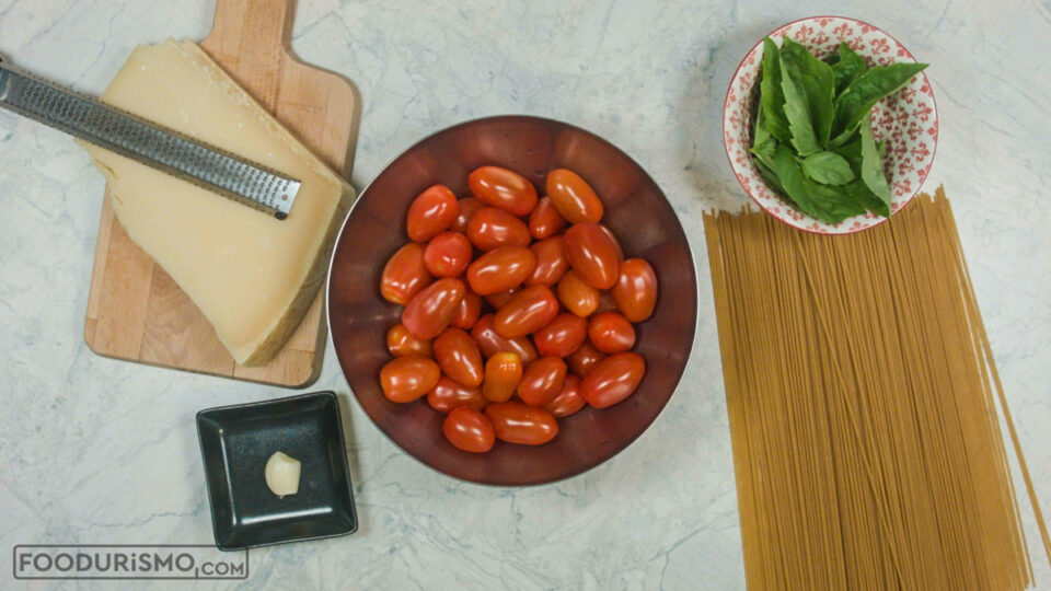ingredients for pasta with garlic, cherry tomatoes, basil, and parmesan